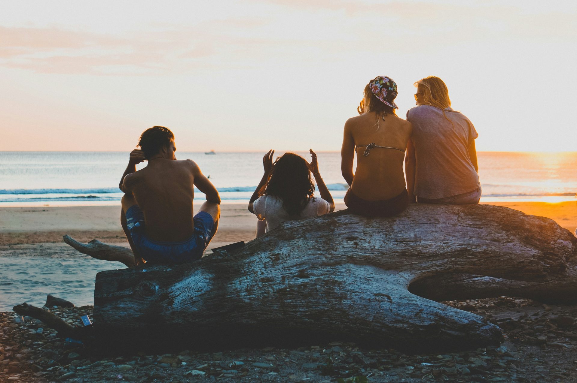 3 mujeres sentadas sobre una roca en la playa durante el día